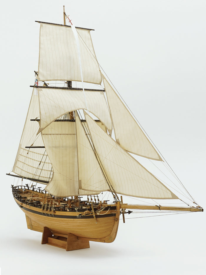 Photo of the HMS Rattlesnake 1776 wooden model kit by Shipyard in 1:72 scale, showing laser-cut parts, brass details, rigging accessories, and sails.